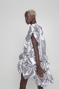 a woman in a silver dress is standing on a white background