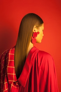 a woman wearing a red coat and red earrings