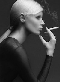 a black and white photo of a woman smoking a cigarette